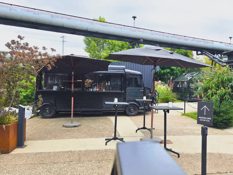 Black food truck with umbrellas along the exhibition path